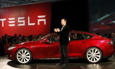 Elon musk standing in front of red tesla