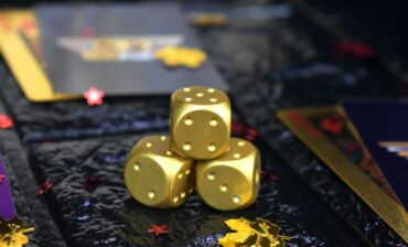 Metal dice on gambling table next to gold coins