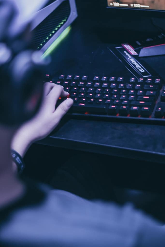 Cropped image of young gamer playing video games on computer